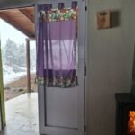 Estufa a leña encendida junto a la puerta de la Cabaña Verde durante la nevada en Villa Yacanto