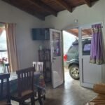 Living de la Cabaña Verde con la estufa a leña encendida y la nieve afuera, en Villa Yacanto