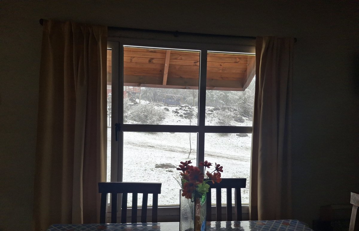 Mesa de la Cabaña Verde frente al ventanal con el paisaje nevado de Villa Yacanto